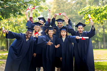 Image showing happy students in mortar boards with diplomas