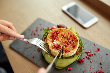 Image showing woman eating goat cheese salad at restaurant