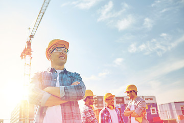 Image showing group of smiling builders in hardhats outdoors