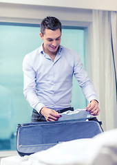 Image showing businessman packing things in suitcase