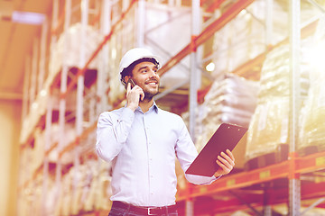 Image showing man with clipboard and smartphone at warehouse