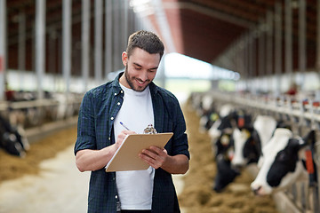 Image showing farmer with clipboard and cows in cowshed on farm