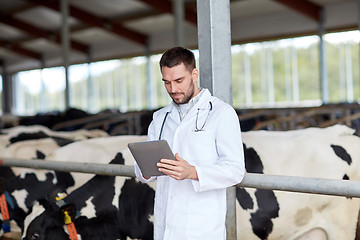 Image showing veterinarian with tablet pc and cows on dairy farm