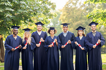 Image showing happy students in mortar boards with diplomas