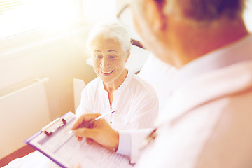 Image showing senior woman and doctor with clipboard at hospital