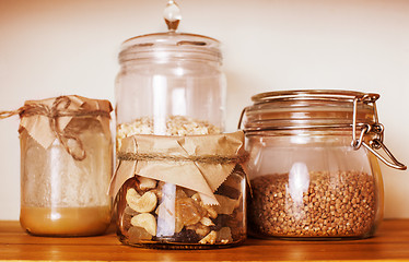 Image showing real comfort wooden kitchen with breakfast ingredients close up in glass, honey, oatmeal, milk, muesli