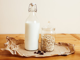 Image showing real comfort wooden kitchen with breakfast ingredients close up in glass, honey, oatmeal, milk, muesli