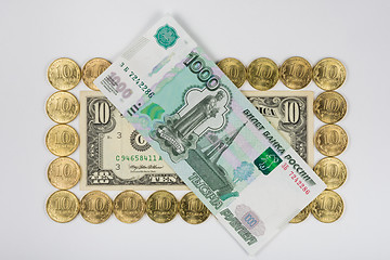 Image showing Ten dollars levied on the perimeter of a ten Russian coins lying on top thousand-bill