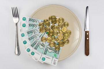 Image showing On the plate is a bunch of Russian ten-thousandths of bills and coins lay near cutlery, top view