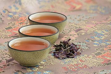 Image showing  three cups filled with tea on a beautiful tablecloth