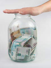 Image showing Hand covered the three-liter jar with Russian money