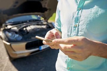 Image showing close up of man with smartphone and broken car