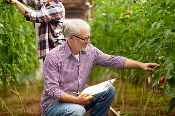 Image showing senior man with clipboard at greenhouse on farm