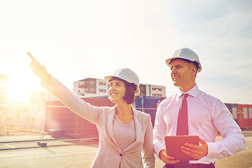 Image showing happy builders in hardhats with tablet pc outdoors