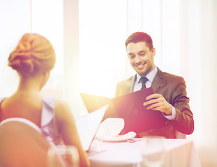 Image showing smiling young man looking at menu at restaurant