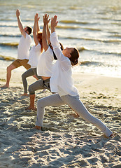 Image showing group of people making yoga exercises on beach