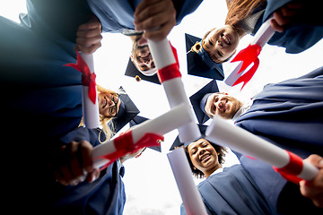 Image showing happy students or bachelors with diplomas