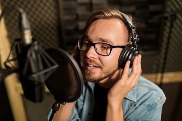 Image showing man with headphones singing at recording studio