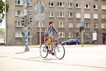 Image showing young hipster man with bag riding fixed gear bike