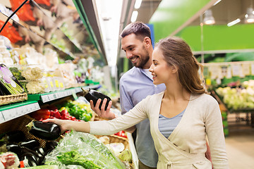 Image showing happy couple buying eggplant at grocery store