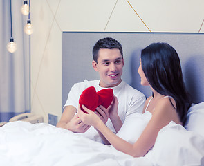 Image showing smiling couple in bed with red heart shape pillow