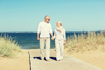 Image showing happy senior couple holding hands on summer beach