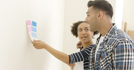 Image showing Young couple trying to choose a paint color