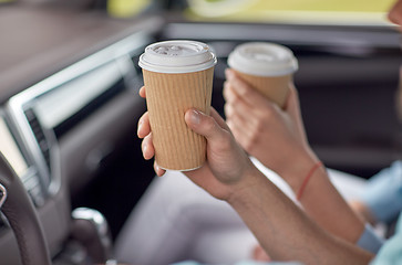 Image showing close up of couple driving in car with coffee cups