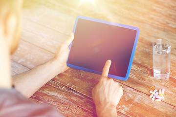 Image showing close up of hands with tablet pc, pills and water