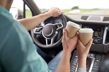 Image showing close up of couple driving in car with coffee cups