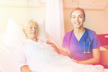 Image showing doctor or nurse visiting senior woman at hospital