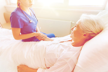 Image showing doctor or nurse visiting senior woman at hospital