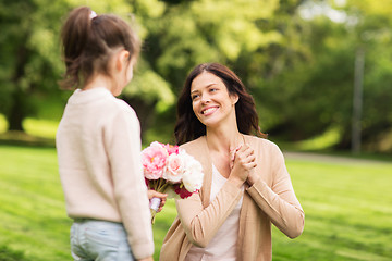 Image showing girl giving with flowers to mother in summer park