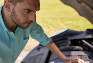 Image showing man with open hood of broken car at countryside