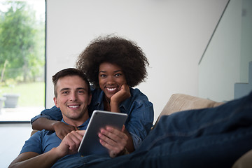 Image showing multiethnic couple relaxing at  home with tablet computers