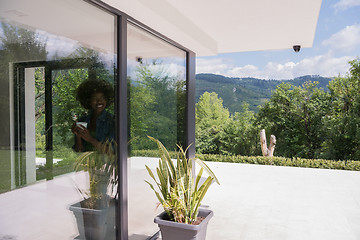 Image showing African American woman drinking coffee looking out the window