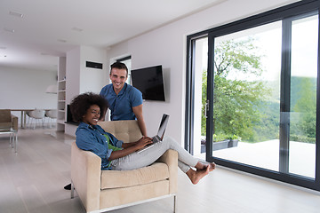 Image showing multiethnic couple on an armchair with a laptop