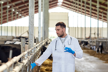 Image showing veterinarian with syringe vaccinating cows on farm