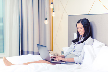 Image showing happy businesswoman with laptop in hotel room