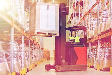 Image showing man with tablet pc operating forklift at warehouse