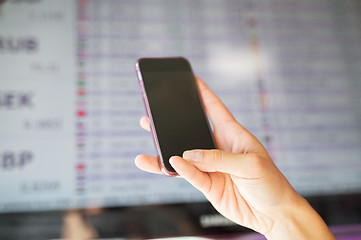 Image showing hand with smartphone over exchange rates on screen