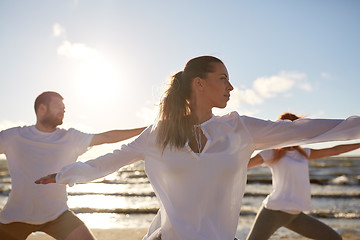 Image showing group of people making yoga exercises on beach