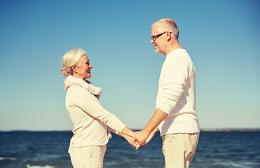 Image showing happy senior couple holding hands summer beach