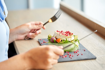 Image showing woman eating goat cheese salad at restaurant