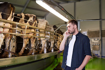 Image showing man calling on cellphone and cows at dairy farm