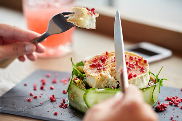 Image showing woman eating goat cheese salad at restaurant