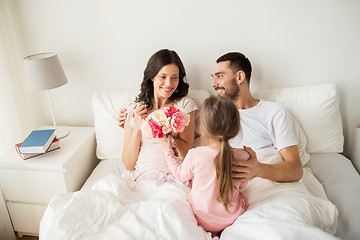 Image showing happy girl giving flowers to mother in bed at home