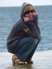 Image showing Youn Lady in Hood Sitting near Sea