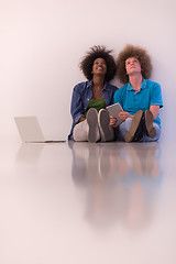 Image showing multiethnic couple sitting on the floor with a laptop and tablet