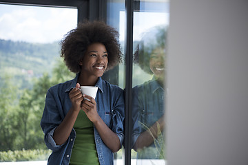 Image showing African American woman drinking coffee looking out the window